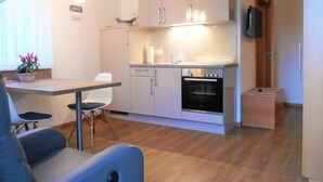 A compact kitchen with a dining area, a built-in oven, and a television on the wall.