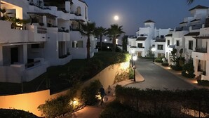 Zona residencial con edificios blancos, un camino curvo y una luna creciente en el cielo.
