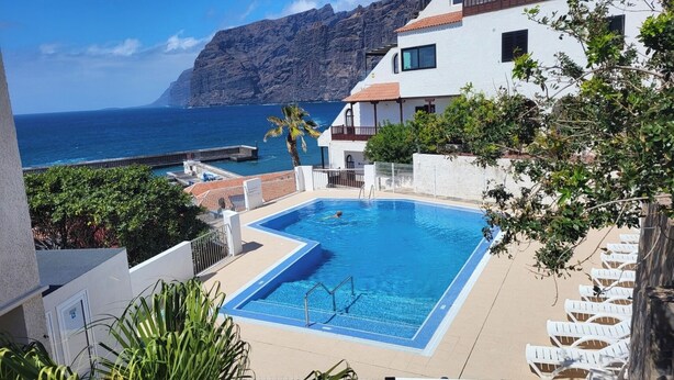 A swimming pool with a view of the ocean and a mountain in the background. - Apartment with sun terrace and panoramic sea view, 5 min. from harbor + beach (Los Gigantes)