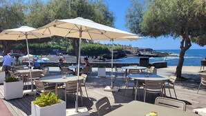 An outdoor dining area with tables and chairs, umbrellas, and a view of the ocean. - Apartment with sun terrace and panoramic sea view, 5 min. from harbor + beach (Los Gigantes)