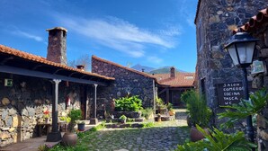 A stone building with a tiled roof, a sign indicating a salon, and a cobblestone courtyard with potted plants. - Apartment with sun terrace and panoramic sea view, 5 min. from harbor + beach (Los Gigantes)