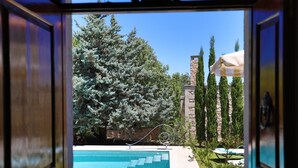 Vista de una piscina con un muro de piedra y  árboles al fondo.