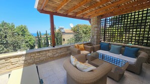 A balcony with wicker furniture, stone walls, and a view of the sea. - Villa Sifina, natural stone villa with sea view. 5 minutes drive to the beach, (Rethymno)