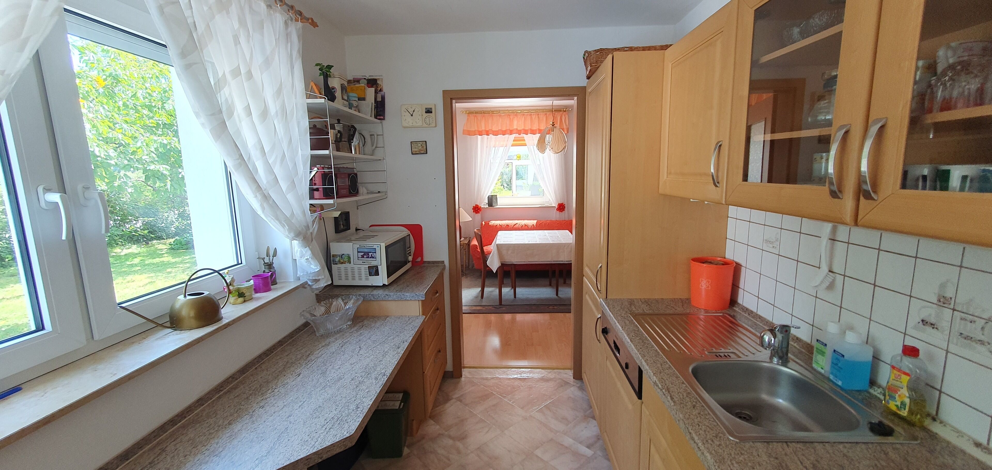 Eine Küche mit Fenster, Mikrowelle und Spüle.