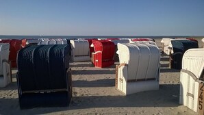 Reihenweise Strandkörfe aus Weidwerk am sandigen Strand.