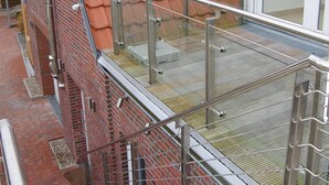 Eine Treppe führt zu einem Dach mit roten Ziegeln, einem Glasgeländer und einem Fenster.