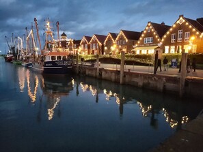 A waterfront with traditional buildings, a dock with boats, and a pedestrian walkway.