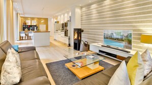 A modern living room with a glass coffee table, leather sofa, and a television. - Luxury Seebrise Binz: Fireplace, Park Setting, and Perfect for a Vacation with Your Dog (Binz)