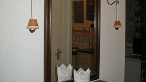 A mirror with two wall-mounted sconces, a wooden shelf below, and a lace doily on the shelf.