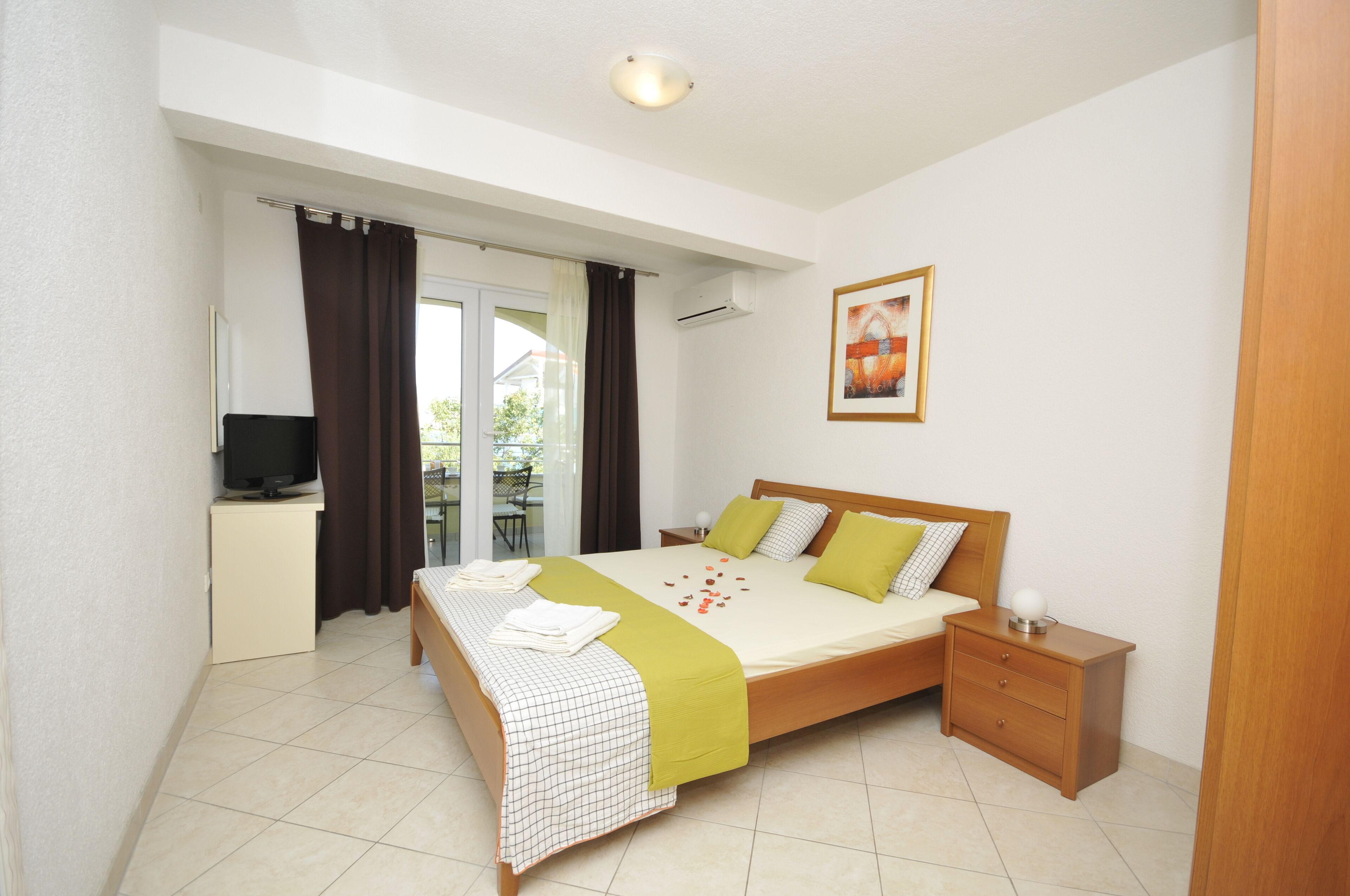 A bedroom with a bed, bedside table, and a TV on a stand.