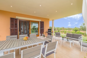 Un patio con mesa lista para comer, asientos al aire libre y una parrilla.