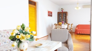 Un comedor con una mesa lista para dos personas, un jarrón floral y sillas alrededor de la mesa.