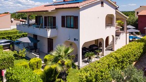 Une maison à deux étages avec un balcon, une piscine et un jardin.