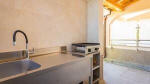 Une cuisine moderne dotée d’un évier en acier inoxydable, d’une cuisinière encastrée et offrant une vue sur le balcon extérieur.