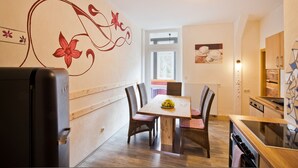Un coin repas avec une table en bois, des chaises en osier et un panier de fruits.