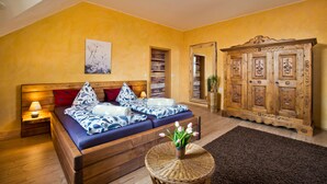 Une chambre avec un lit en bois, une armoire en bois et une petite table ronde sur laquelle est posée une plante.