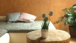 Un salon moderne avec une table basse ronde en bois, une petite plante en pot et un canapé agrémenté de coussins à motifs.