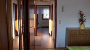Una habitación con cama, armario de madera y ventana con cortinas.