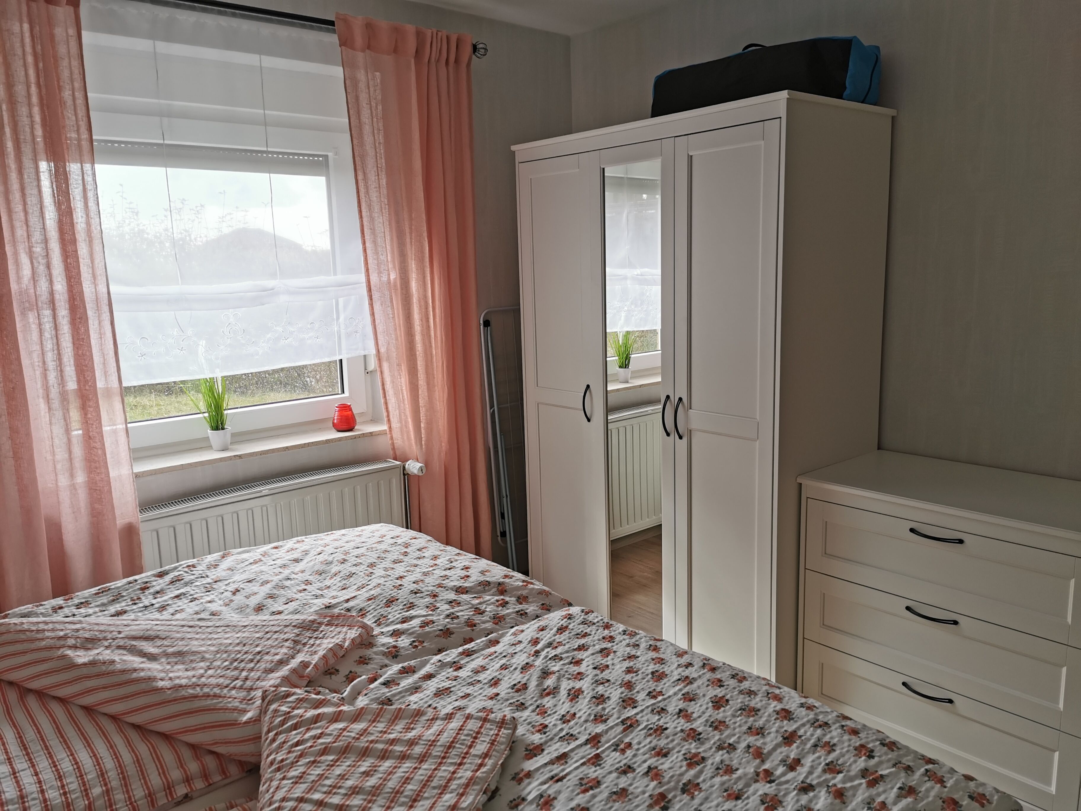 Une chambre à coucher avec un lit, une armoire et une fenêtre avec des rideaux.