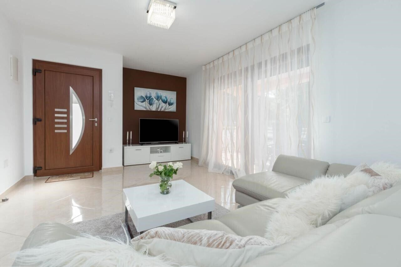 Ein modernes Wohnzimmer mit Sofa, Couchtisch, Fernseher und einer Tür.