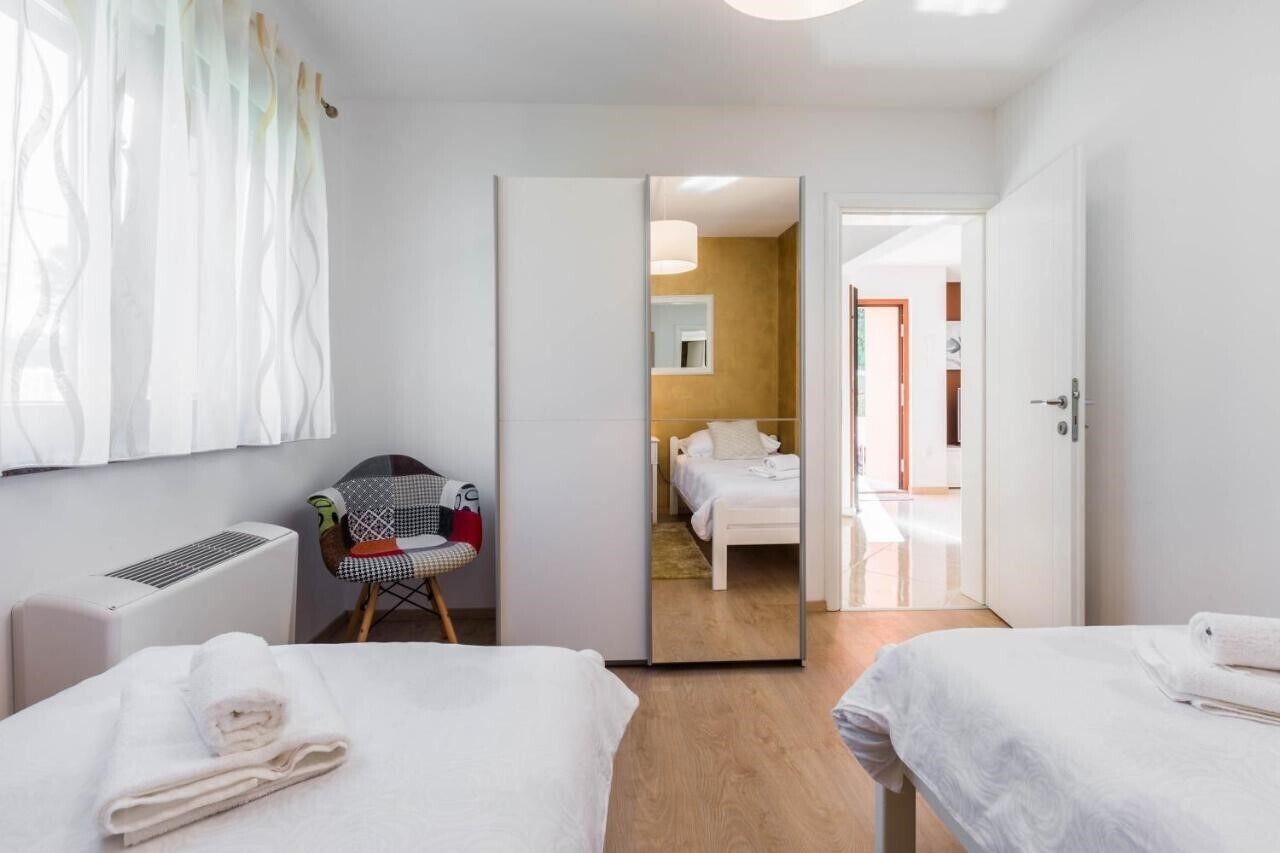 Une chambre d’hôtel avec deux lits, une chaise, un miroir et une vue sur la chambre voisine.