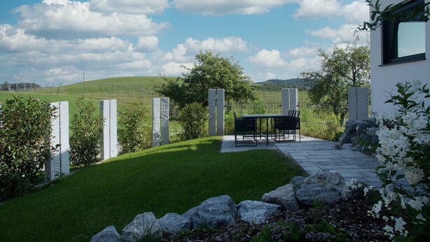 A modern house with a stone pathway leading to a patio with a table and chairs. - Vacation magic  (Neukirch)