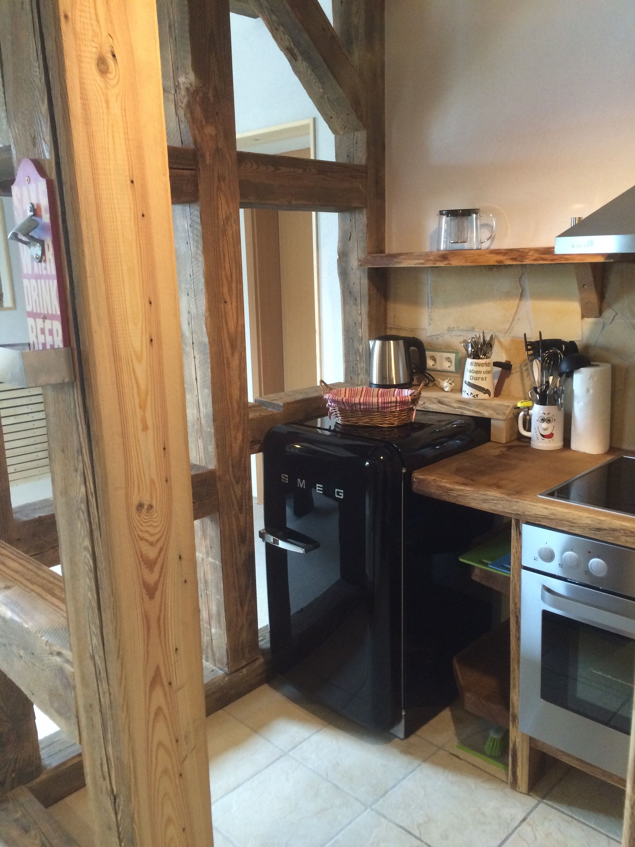 A kitchen with a black stove, a wooden countertop, and a stainless steel oven.