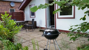 A patio with a grill, outdoor furniture, and a brick house with windows and a door. - Holiday house in the Lüneburg Heath up to 4 people (Suderburg)