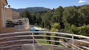 Un balcone con piscina, circondato da vegetazione e montagne.