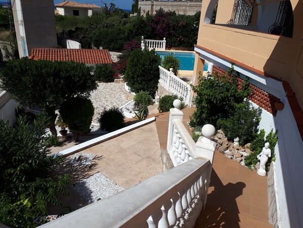 A courtyard with a swimming pool, surrounded by greenery and a white fence. - La Casa - Villa with Views of the Sea and Castle (Dénia)
