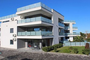 A modern multi-story building with balconies, large windows, and a paved courtyard.