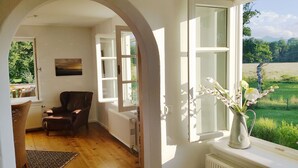 A room with a wooden floor, a brown leather chair, a white radiator, and a painting on the wall.