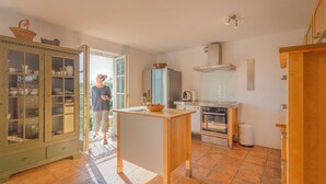 A modern kitchen with a central island, a built-in oven, and a cabinet with glass doors.