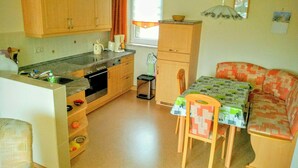 Una cocina compacta con armarios de madera, horno integrado y una pequeña mesa con mantel estampado.