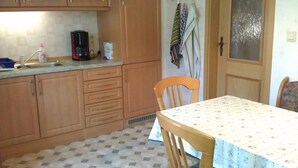 Eine Küche mit Holzschränken, einer Kaffeemaschine und einem Tisch mit gemustertem Tischläufer.