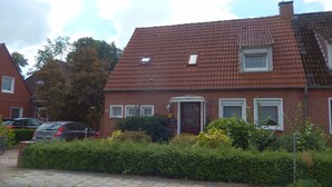 Ett hus byggt av rött tegel med ett tak täckt av takpannor, en liten veranda och siffran ’25’ på fasaden.