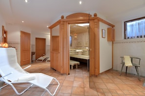 Um quarto com um arco de madeira, uma cadeira branca, um banco de madeira e uma pequena mesa.