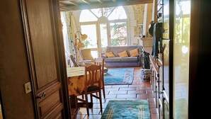 A kitchen with a wooden door, a dining table with chairs, a sofa, and a rug. - Bright duplex apartment with terrace and beautiful views (Cornillon)