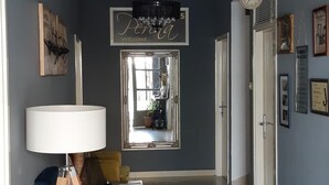Ein geräumiger Flur mit einer modernen Leuchte, einem blauen Sofa und einer Stehlampe.