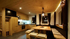 A wooden kitchen with a large dining table, benches, and a television. - Mountain chalet Zillertal, near Spieljochbahn, cozy and familiar and quiet (Fügenberg)