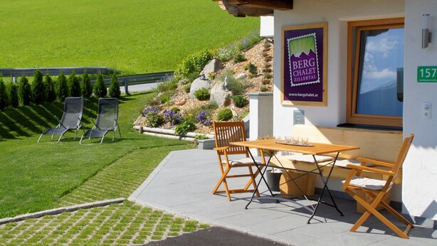 A patio with a table and chairs, a wooden bench, and a sign for Berg Chalet Zillertal. - Mountain chalet Zillertal, near Spieljochbahn, cozy and familiar and quiet (Fügenberg)