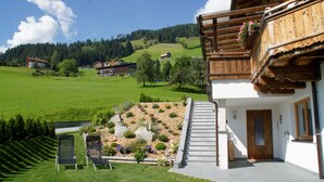 A chalet with a wooden balcony, a stone staircase, and a garden with a variety of plants and flowers. - Mountain chalet Zillertal, near Spieljochbahn, cozy and familiar and quiet (Fügenberg)