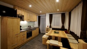 A modern kitchen with wooden cabinets, a built-in microwave, and a dining area with a wooden table and benches. - Mountain chalet Zillertal, near Spieljochbahn, cozy and familiar and quiet (Fügenberg)