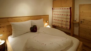A neatly made bed with white linens, a wooden headboard, and a bedside table with a lamp. - Mountain chalet Zillertal, near Spieljochbahn, cozy and familiar and quiet (Fügenberg)