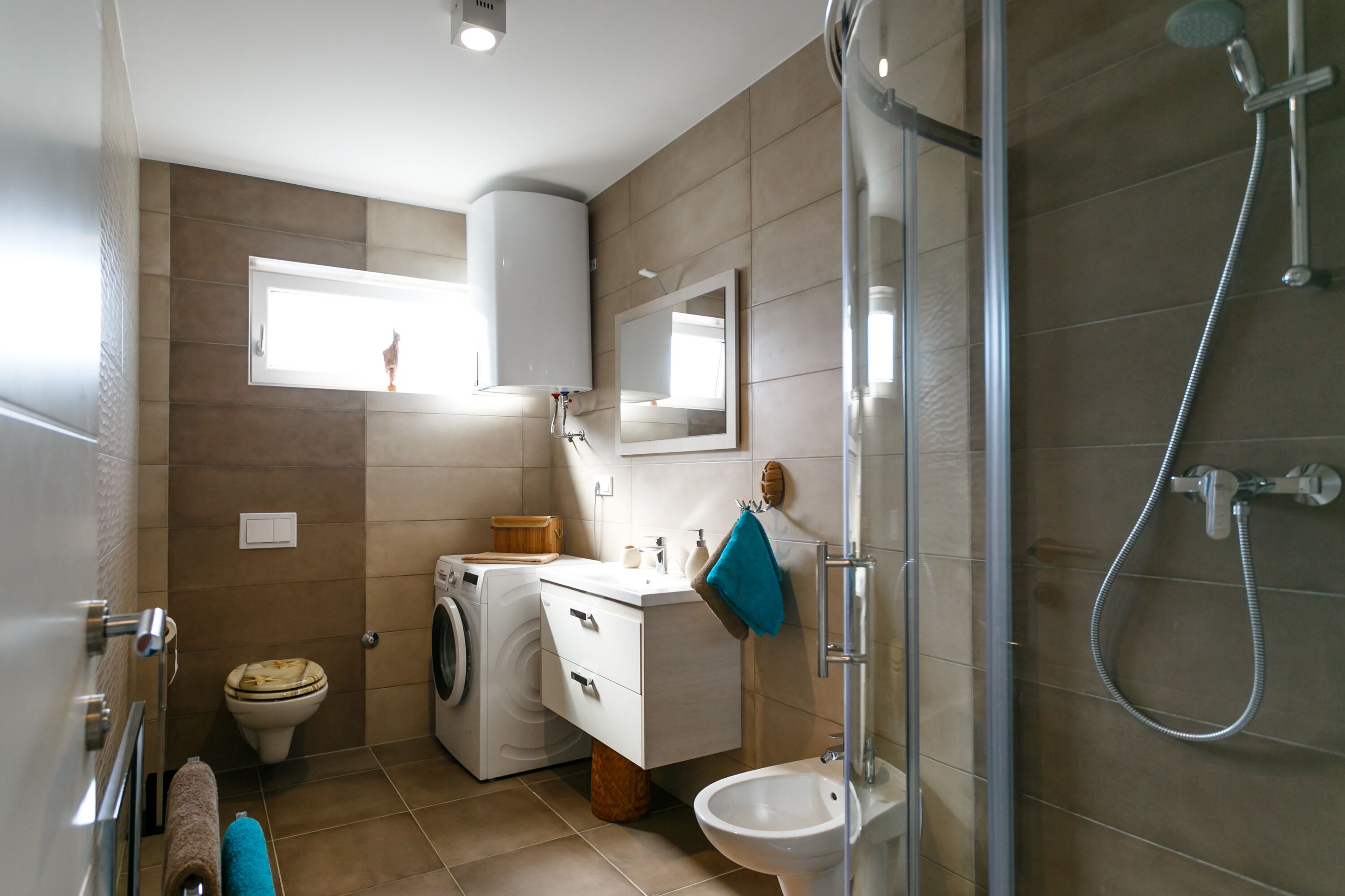 Un baño pequeño con lavadora, lavamanos, inodoro y ducha.