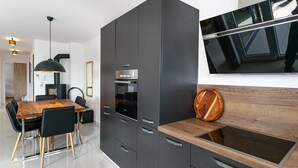 A modern kitchen with dark cabinetry, a wooden dining table, and a built-in stove. -  Relax with a view of the sea !! (Vantacici-Malinska)