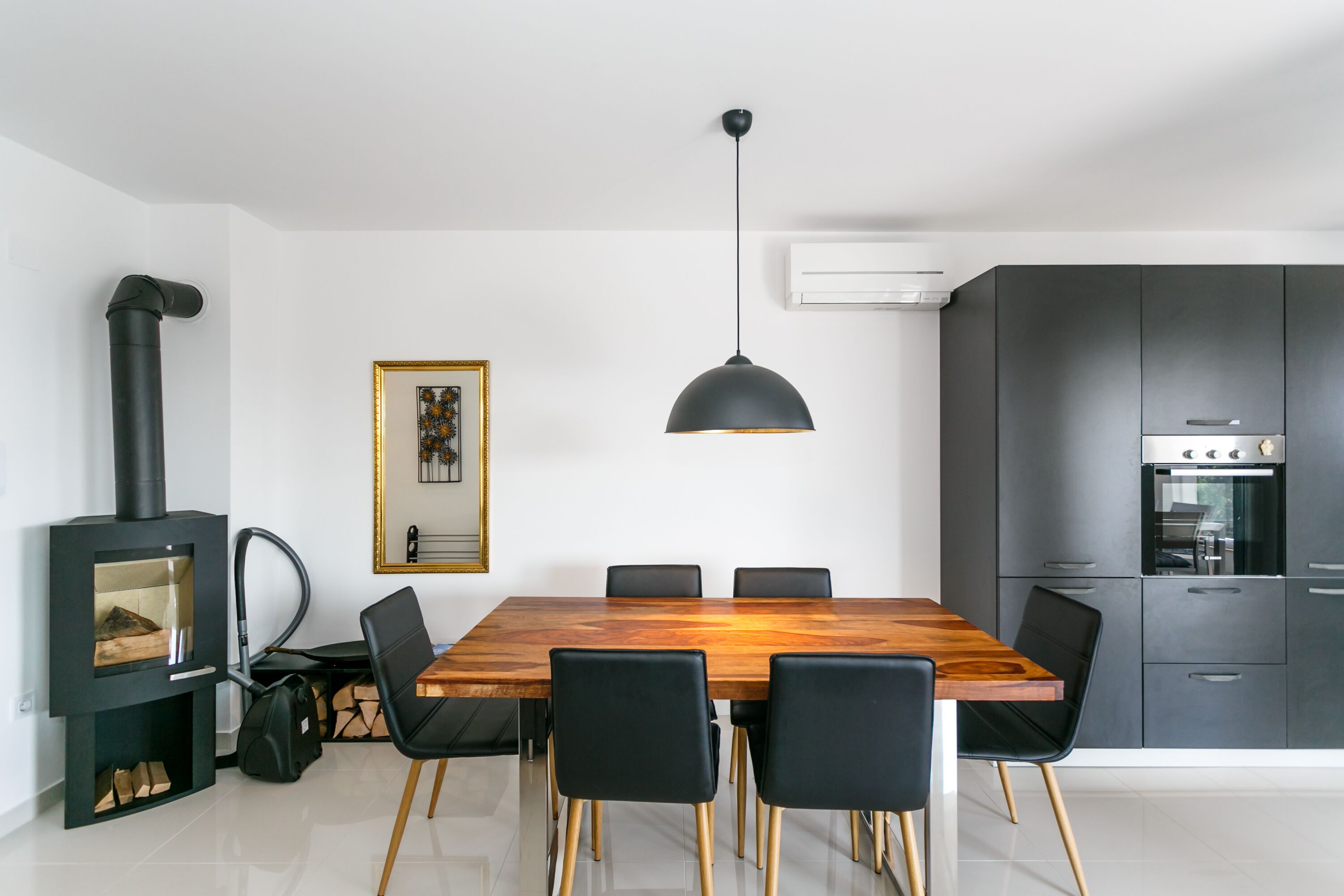 A modern kitchen with a built-in stove, a dining table with chairs, and a pendant light.