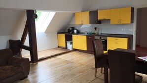 Une cuisine moderne avec des meubles de couleur jaune et marron, un coin repas avec des chaises marron et un plancher en bois.