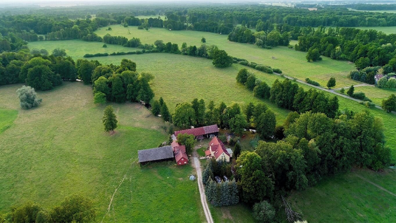 Vue aérienne d’une propriété rurale comprenant une ferme, des champs ouverts et quelques arbres dispersés.