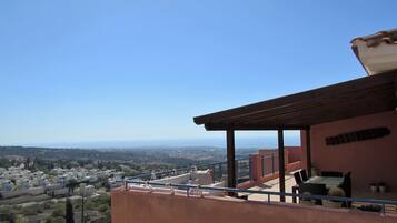Enjoy breathtaking views from this high-rise balcony with a pergola and metal railing.